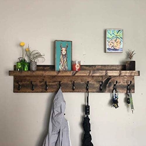 The coat rack holding a jacket, umbrella, and keys, while the shelf displays some plants and picture frames.