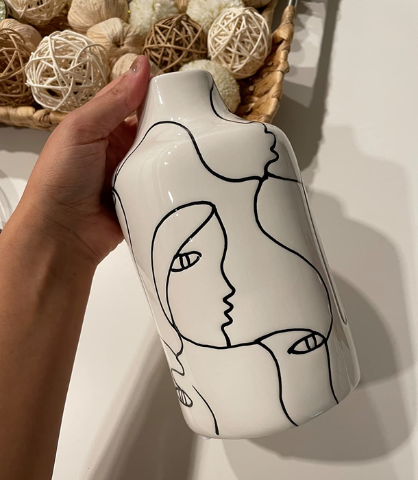 Reviewer holding a stylish black-and-white ceramic vase with a unique abstract design.