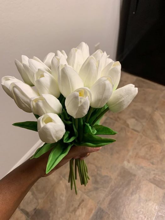 A reviewer holding a bouquet of artificial white tulips