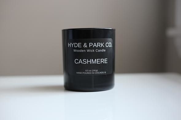 A cashmere-scented candle is displayed in a sleek, minimalist black jar.