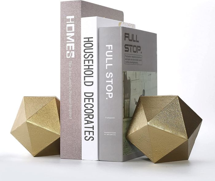 The gold geometric bookends holding three books together