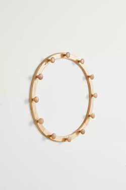 A round wooden wall hook rack with several pegs, ideal for hanging accessories and keeping things neatly arranged.