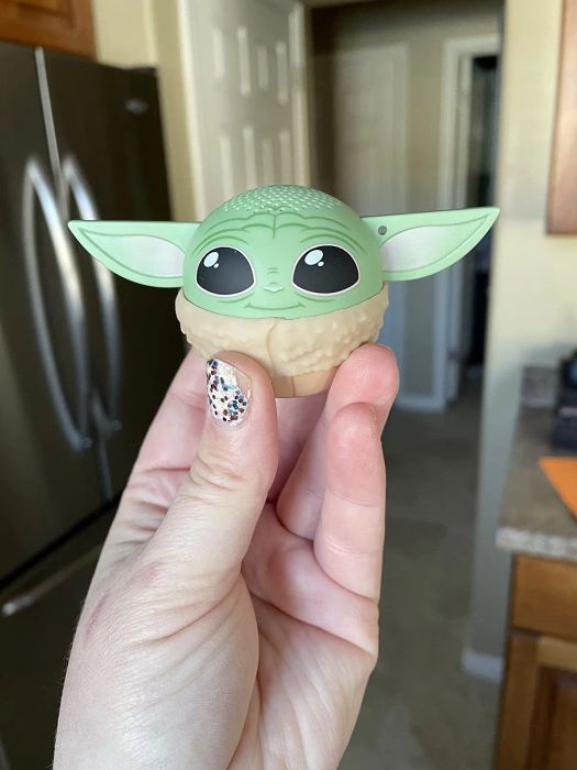 A hand holding up the small but mighty Baby Yoda speaker