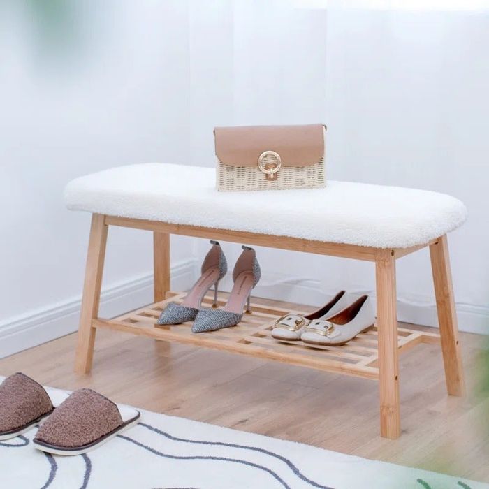 The white storage bench with two pairs of shoes on the lower shelf and a purse resting on top.