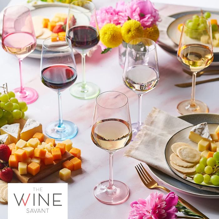 Six elegant stemmed wine glasses in soft, translucent pastel hues