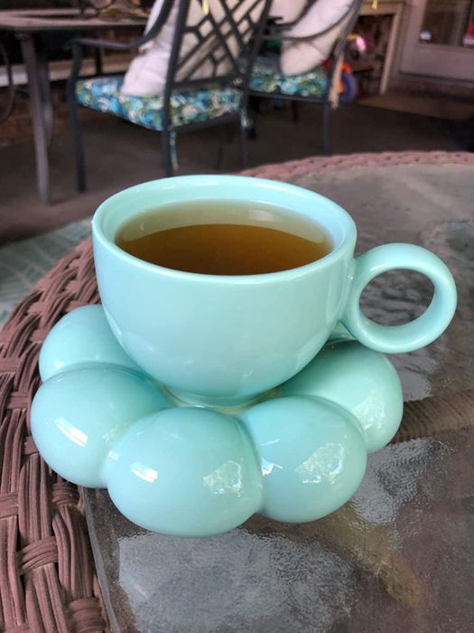 A blue coffee mug filled with tea, resting on a sunflower coaster