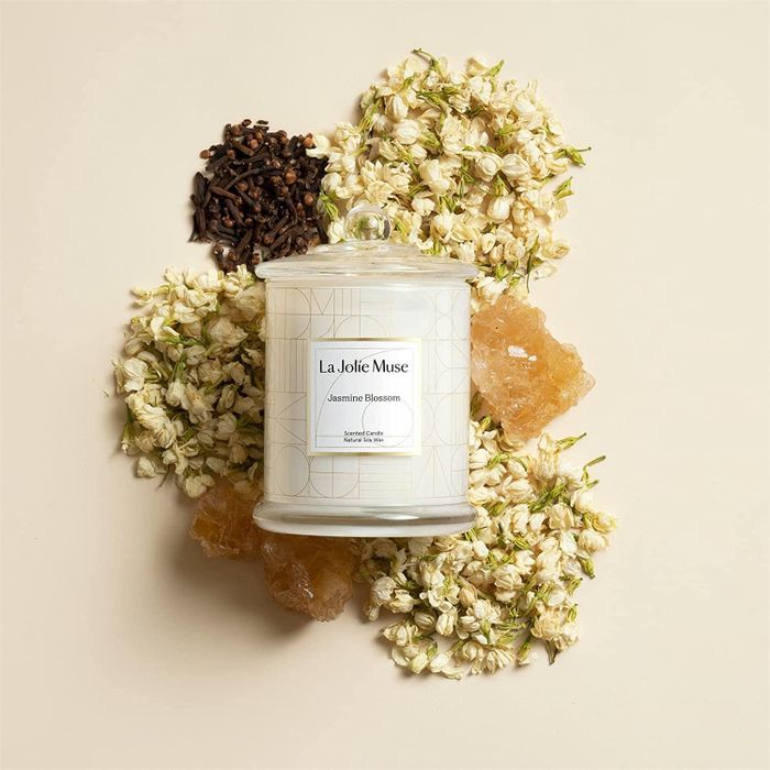 candle in a glass jar surrounded by dried flowers and honeycomb accents