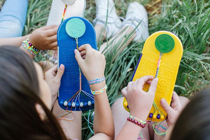 Two kids wearing vibrant friendship bracelets on their wrists and actively creating more