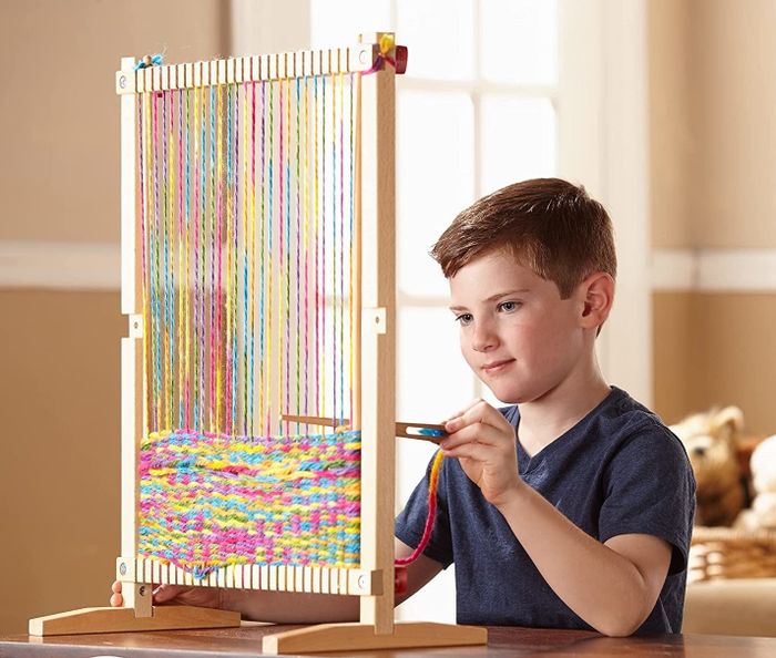 Model using a wooden loom on a table