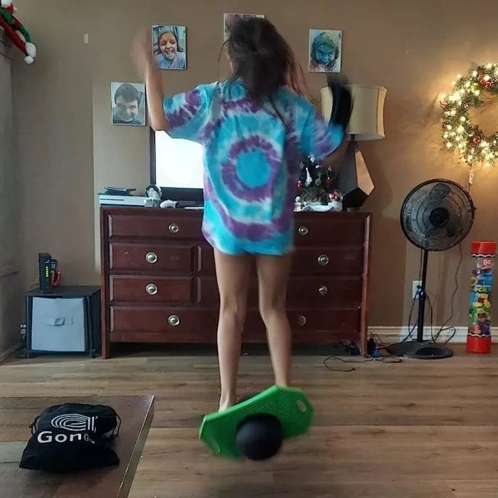 A reviewer's photo showing a child using a green and black pogo ball indoors for size comparison
