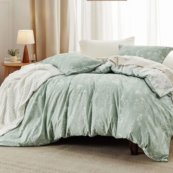 A light green comforter and pillows arranged on a bed in a bedroom