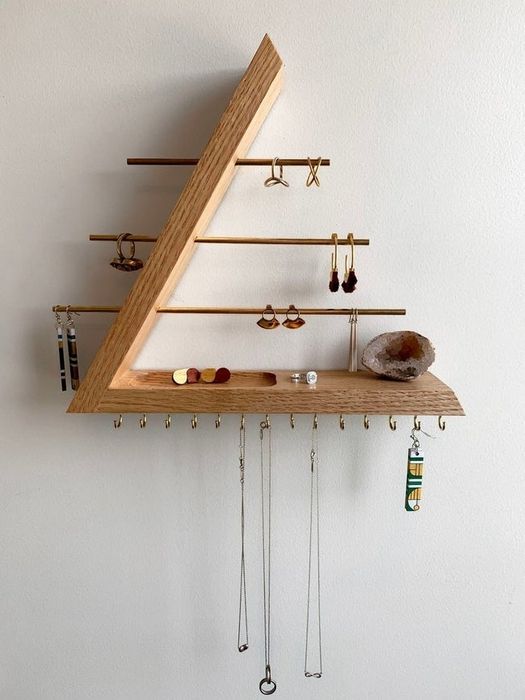 The oak and brass jewelry holder, filled with earrings, rings, and necklaces.