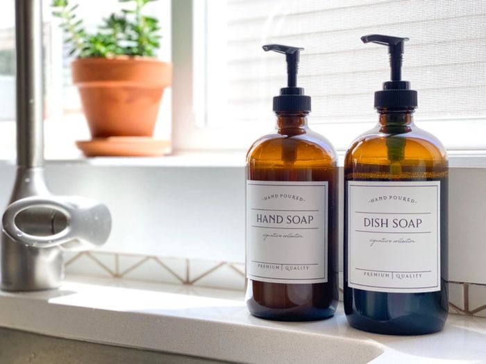 Two refillable hand soap bottles placed beside a kitchen sink