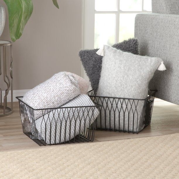 Black metal wire baskets filled with pillows and blankets placed on the floor