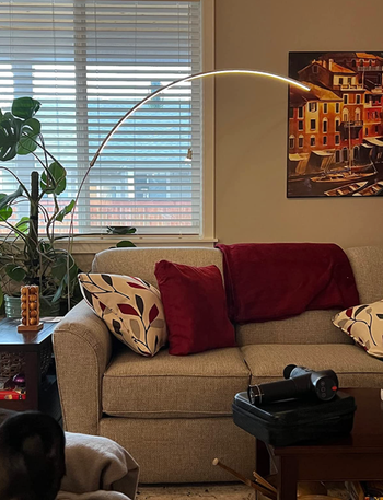 A sleek curved lamp casting a warm glow above a couch