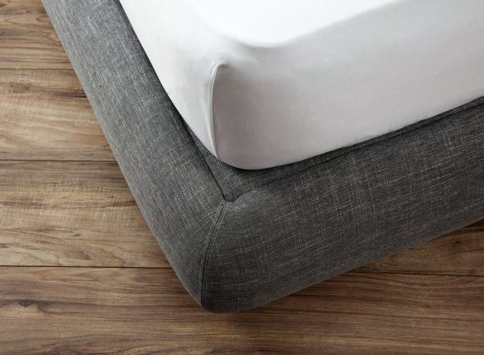 A close-up of the corner of a modern bed frame in elegant gray, showcasing its sleek and stylish design.