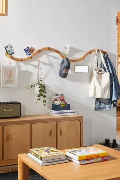 A wall-mounted branch used as a distinctive clothing rack, with various items hanging from it, and a wooden cabinet beneath. Perfect for optimizing small spaces and keeping things organized.