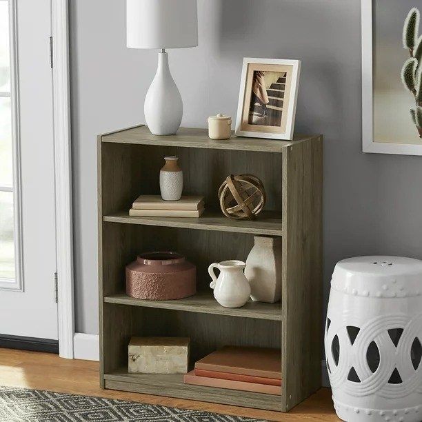 A rustic oak-colored bookcase with shelves full of books and decorative items