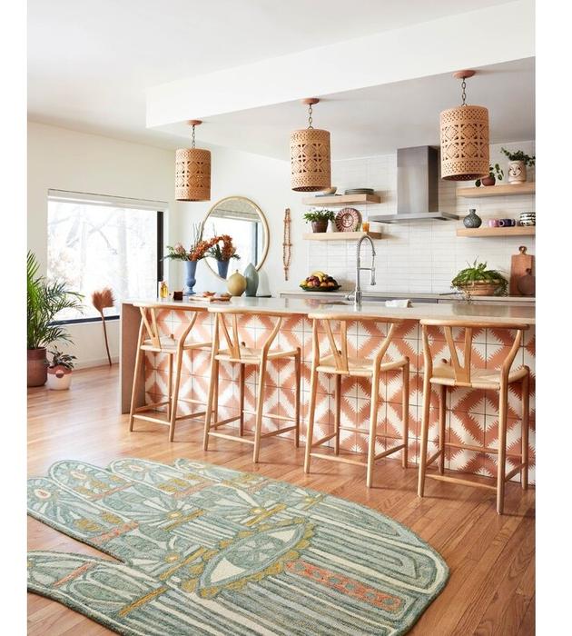 A contemporary kitchen featuring distinctive pendant lights, geometric-patterned bar stools, and a patterned rug.