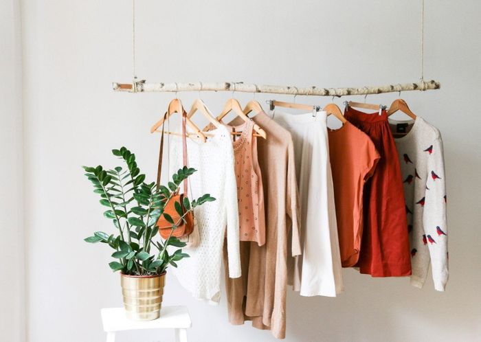 Clothes draped elegantly on the birch branch clothing rack, showcasing its rustic charm.