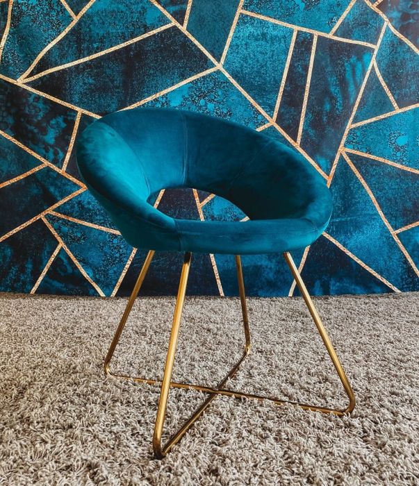 A reviewer’s photo of the blue velvet chair with gold legs.