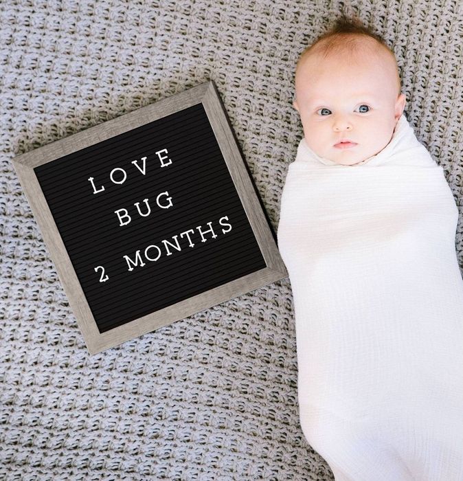 A baby posing next to a letter board
