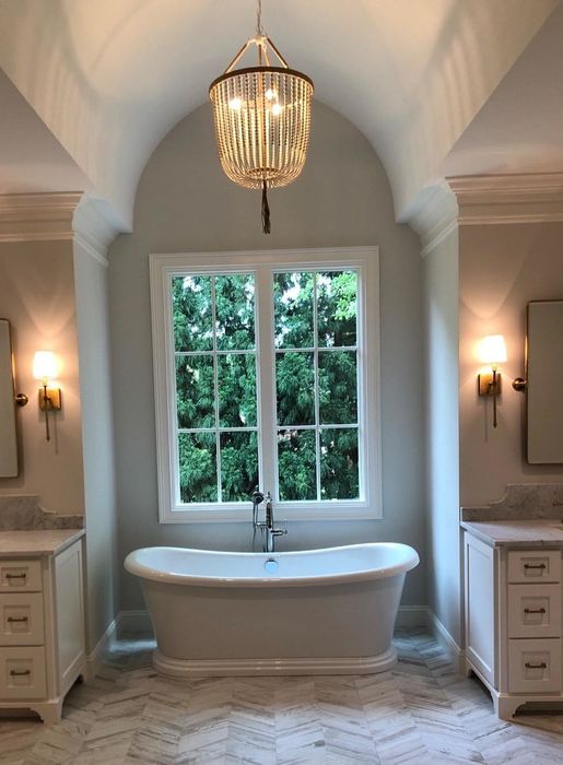A chandelier suspended above a reviewer's bathtub, offering a soft, ambient glow to complement the bathroom's decor.