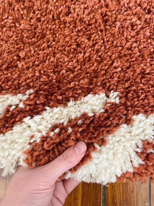 Close-up of Mytourer’s hand lifting the rug to showcase its plush texture.