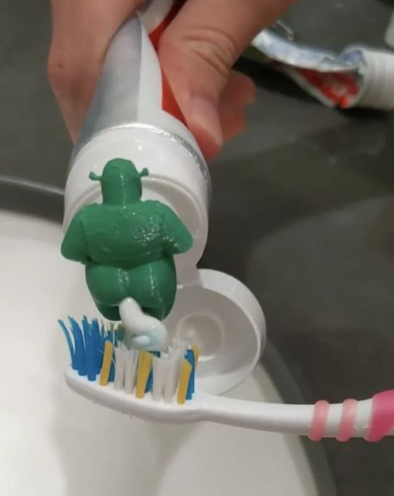 A still image of the 3D-printed green ogre with toothpaste emerging from its backside