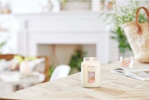 A candle jar placed on a table, casting a soft glow