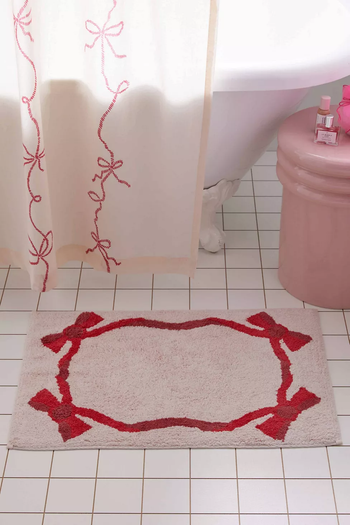 A bathroom setup with a floral shower curtain and a matching bath mat on the tiled floor.