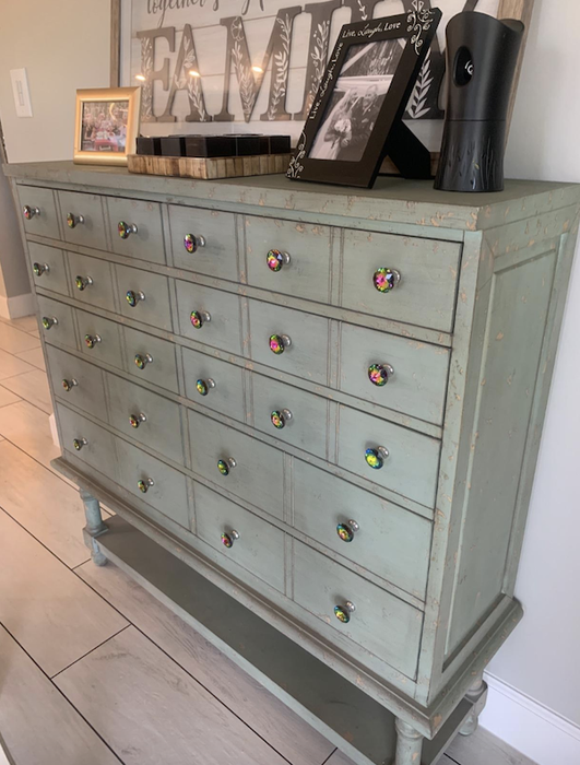 Reviewer photo of a soft green wooden dresser with colorful crystal knobs adorning the drawers.