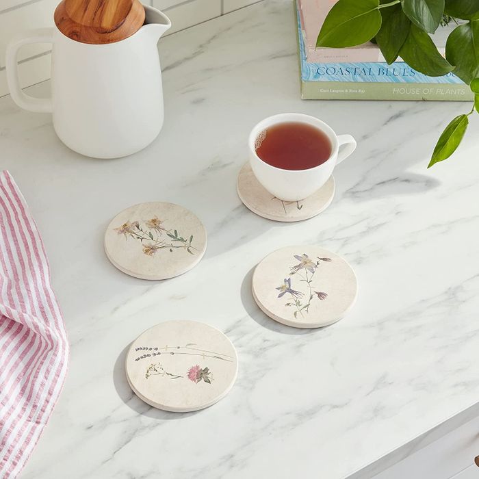 four floral-printed coasters resting on a marble surface