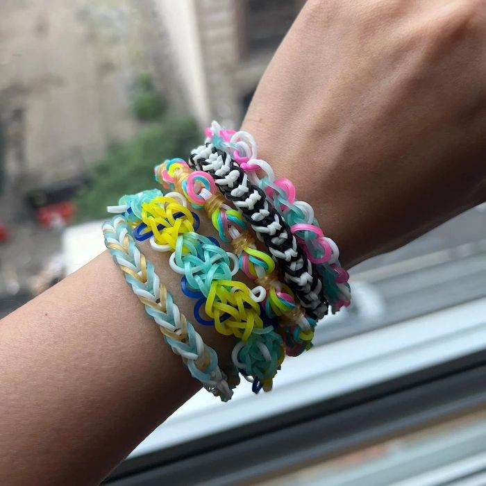 A model's wrist showcasing an array of colorful rubber band bracelets