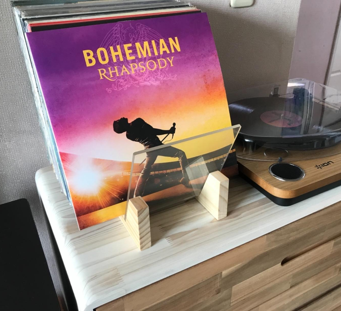 A photo of the natural wood vinyl holder, filled with records and placed next to a record player, adding charm to the room's decor.