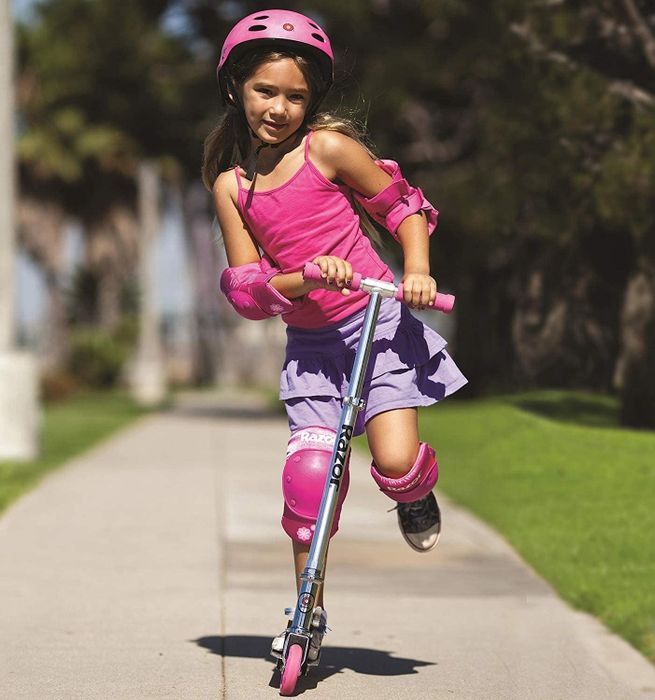 A child enjoying a ride on a pink scooter