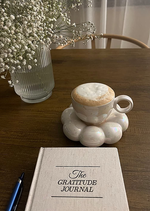 A white coffee mug holding a coffee drink, placed on a sunflower coaster