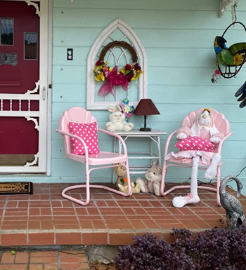 Two pink metal chairs featuring a tulip design on the back, placed on a porch