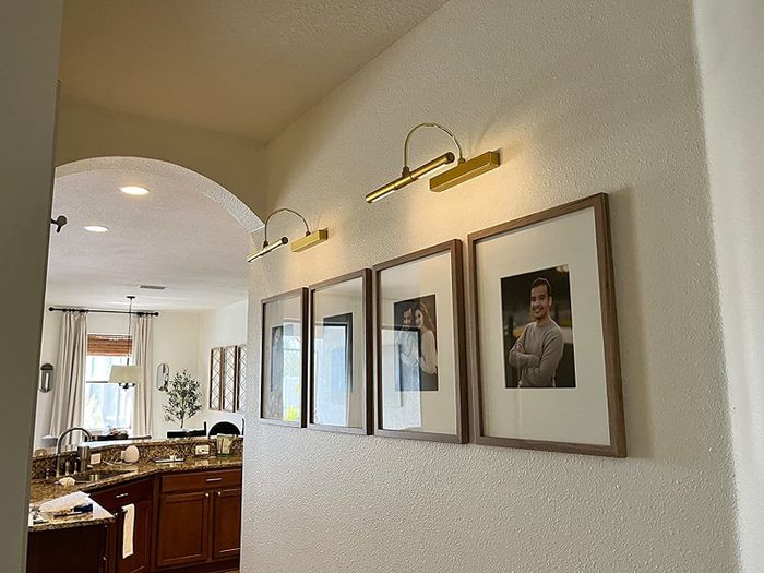 The lights illuminating framed photos on a wall