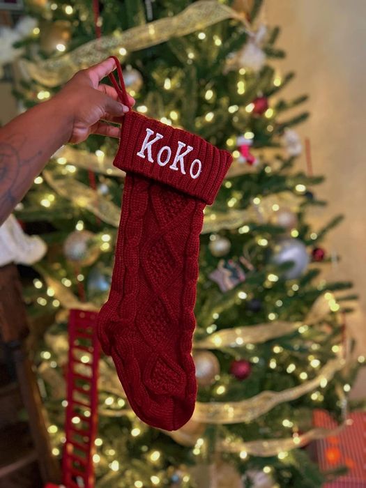 A reviewer holding a red stocking with the name 'Koko' embroidered on it