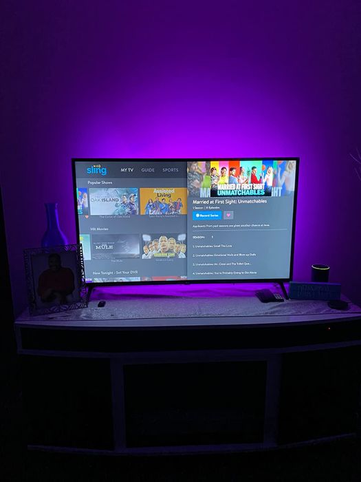 a reviewer demonstrates the purple lights installed behind a TV