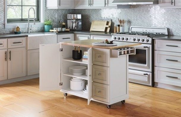 A contemporary kitchen featuring a sleek rolling island cart, fully stocked with kitchen essentials, conveniently placed near the stove.