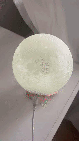 The moon lamp shifting through a spectrum of colors, transitioning from white to red, blue, and purple.