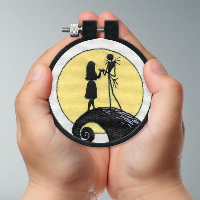 An embroidery hoop displaying the silhouettes of Jack Skellington and Sally from 