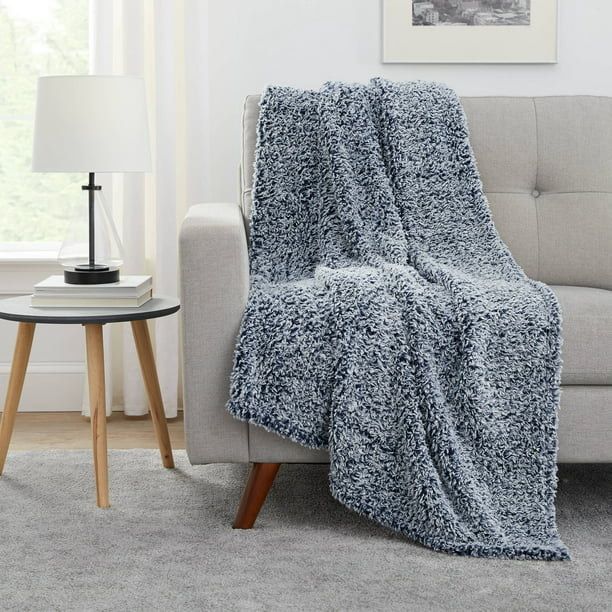 A slate gray sherpa throw blanket elegantly draped over a sofa.