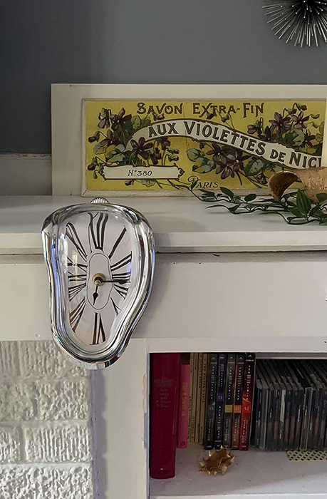 The clock hanging from a reviewer’s bookshelf, melting off the edge