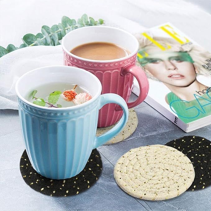 two coffee mugs resting on black and white coasters, each accented with gold details