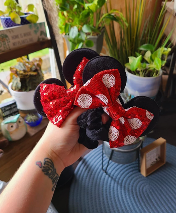 A person holding Minnie Mouse-themed scrunchies 