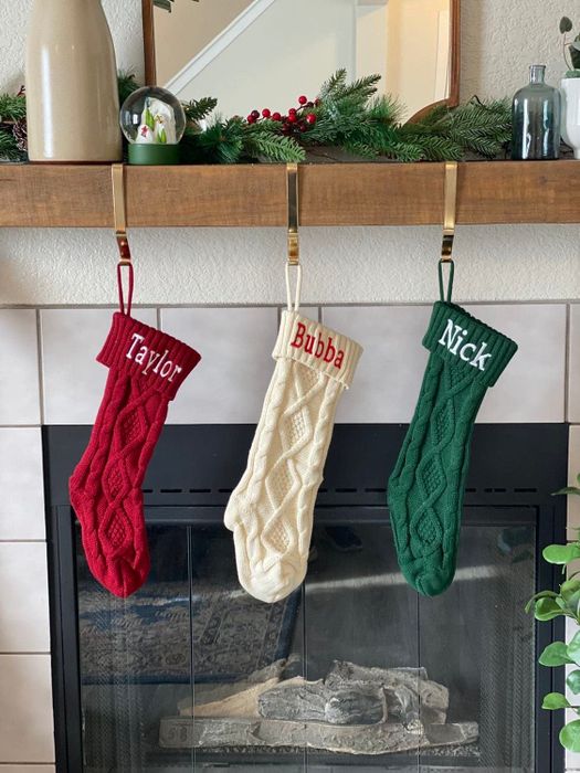 Red, white, and green stockings hanging above a reviewer’s chimney, each with a name beautifully embroidered
