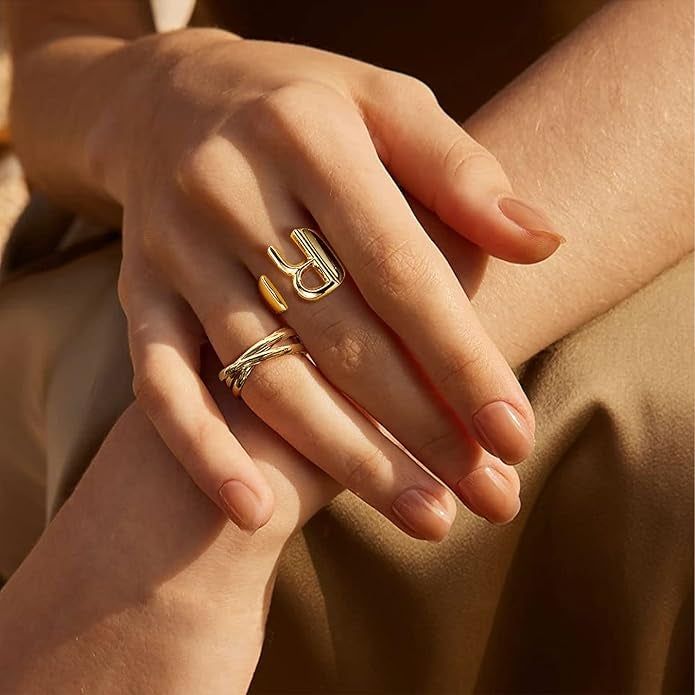 A close-up of hands showcasing trendy gold rings, one featuring a bold design.